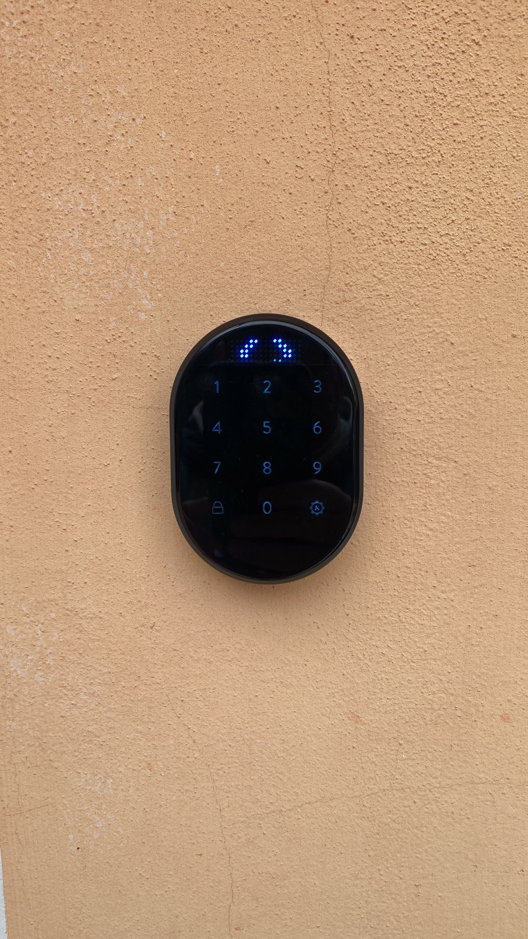 A keypad mounted on a textured beige wall.