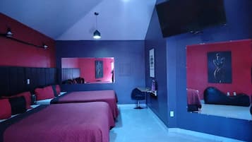 Una habitación de hotel con dos camas, un escritorio, una silla y un televisor en la pared.
