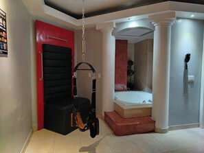 A modern bathroom with a black chair, a hanging exercise device, and a large bathtub. - LIZVAN HOTEL MOTEL (Tijuana)