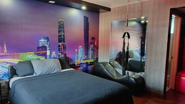 A modern hotel room with a large bed, a massage chair, and a cityscape mural on the wall. - LIZVAN HOTEL MOTEL  (Tijuana)