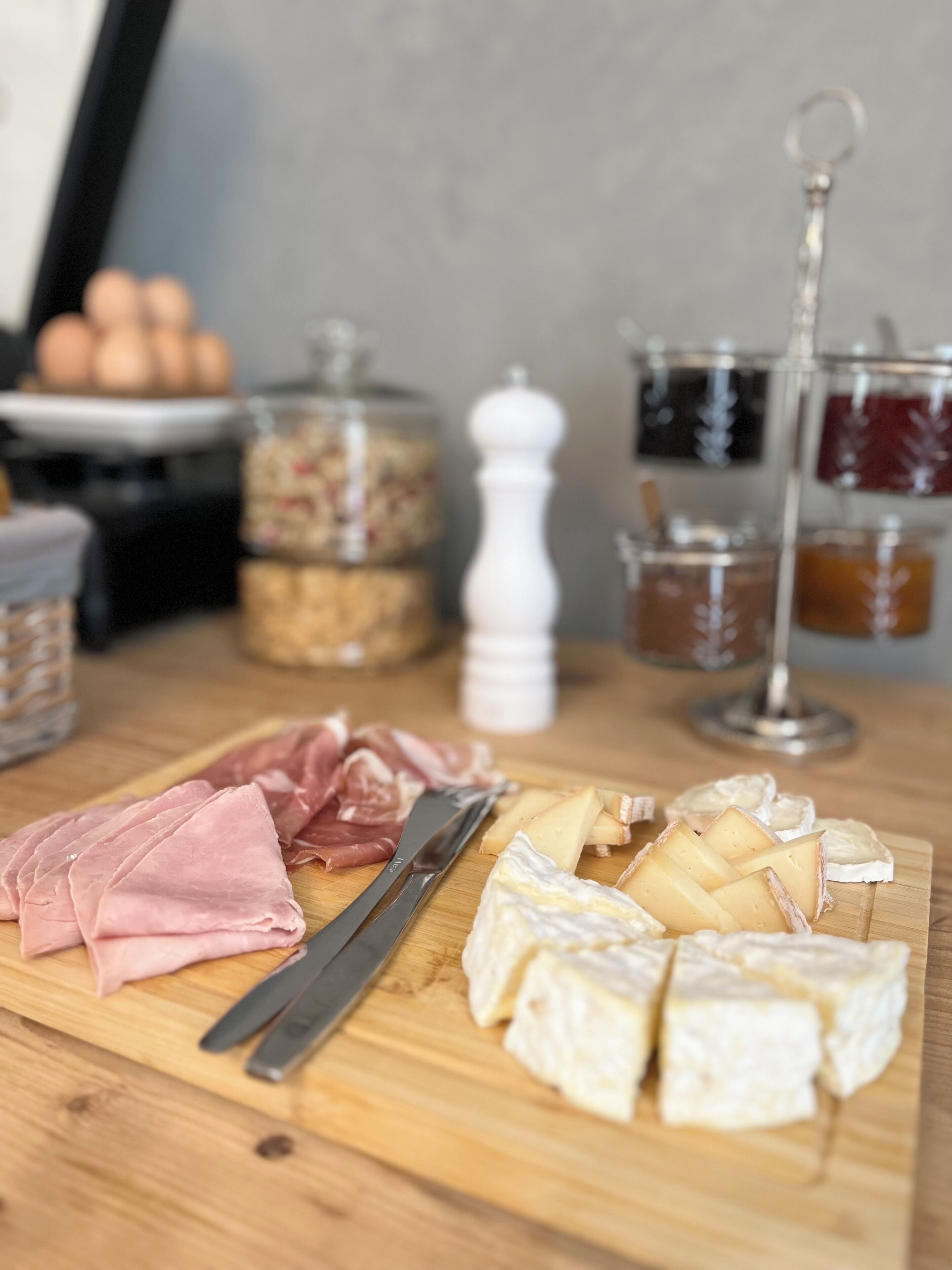 Une planche à découper en bois, sur laquelle sont disposés différents fromages et différentes sortes de charcuterie.