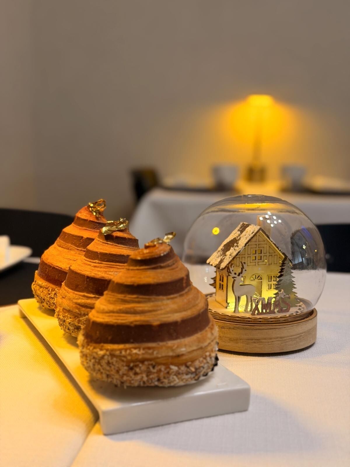 Een tafel met een decoratieve sneeuwbol en drie gelaagde lekkernijen.