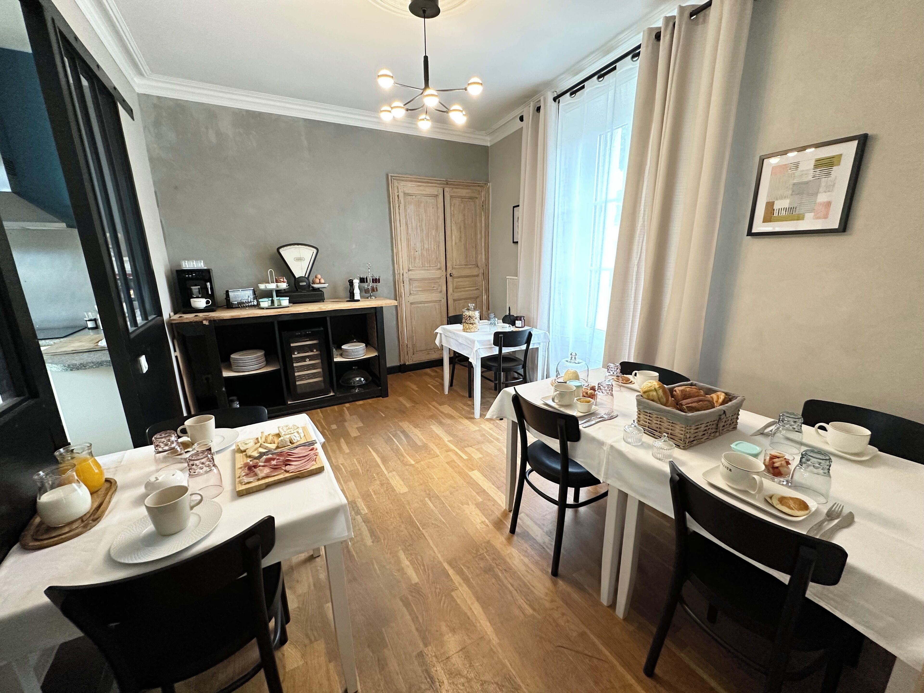 Un espace repas aménagé pour le petit-déjeuner, comprenant des tables, des chaises et des produits pour le petit-déjeuner.