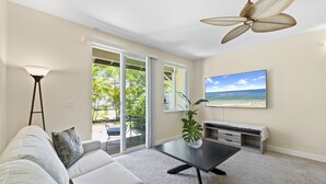 A living room with a sofa, a coffee table, a TV, and a ceiling fan.