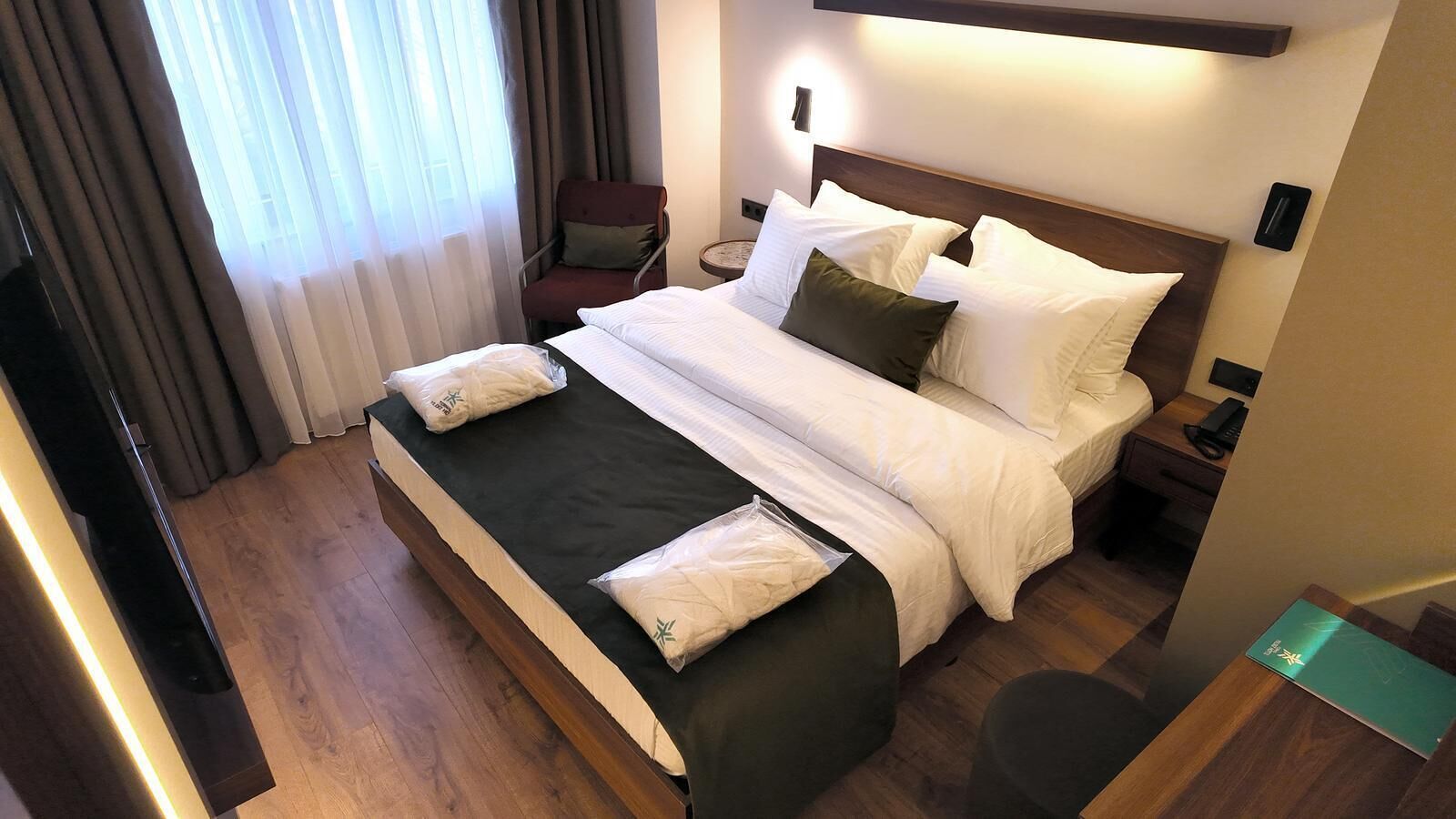 A hotel room with a large bed, bedside tables, a chair, and a desk.