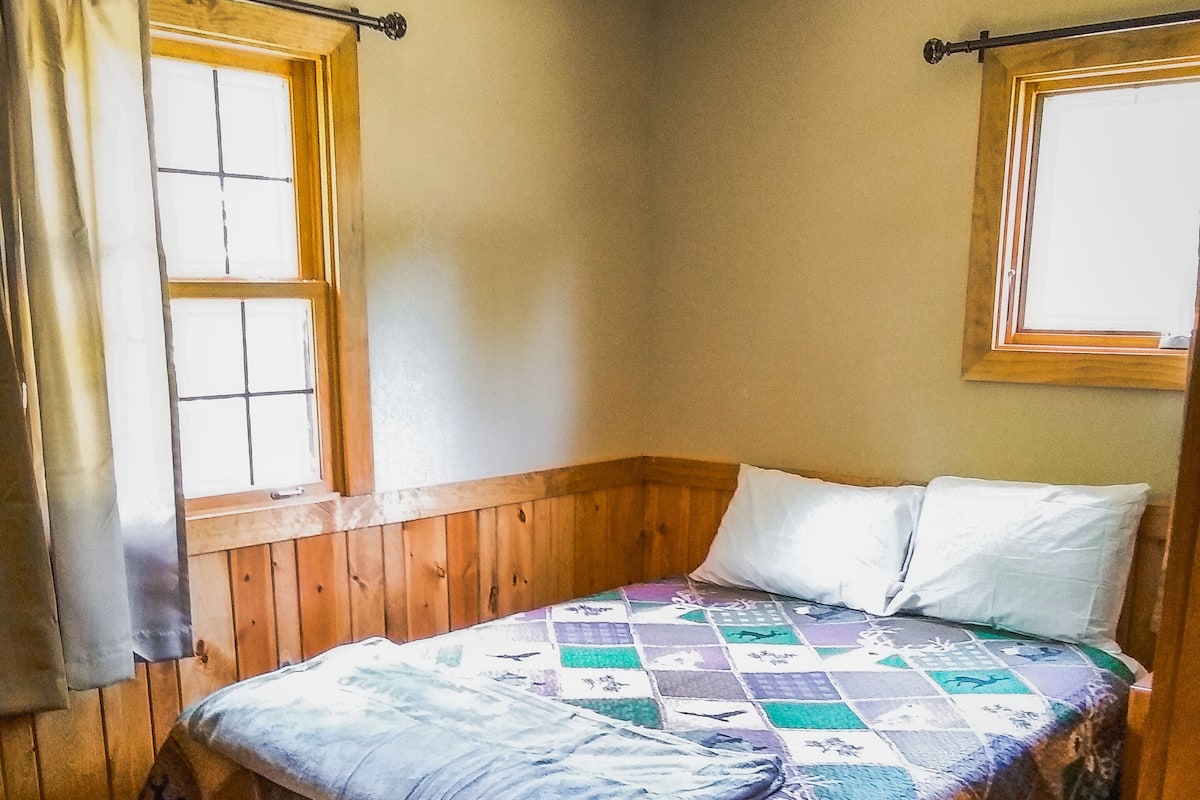 Un dormitorio con una cama de madera, un banco y una ventana.