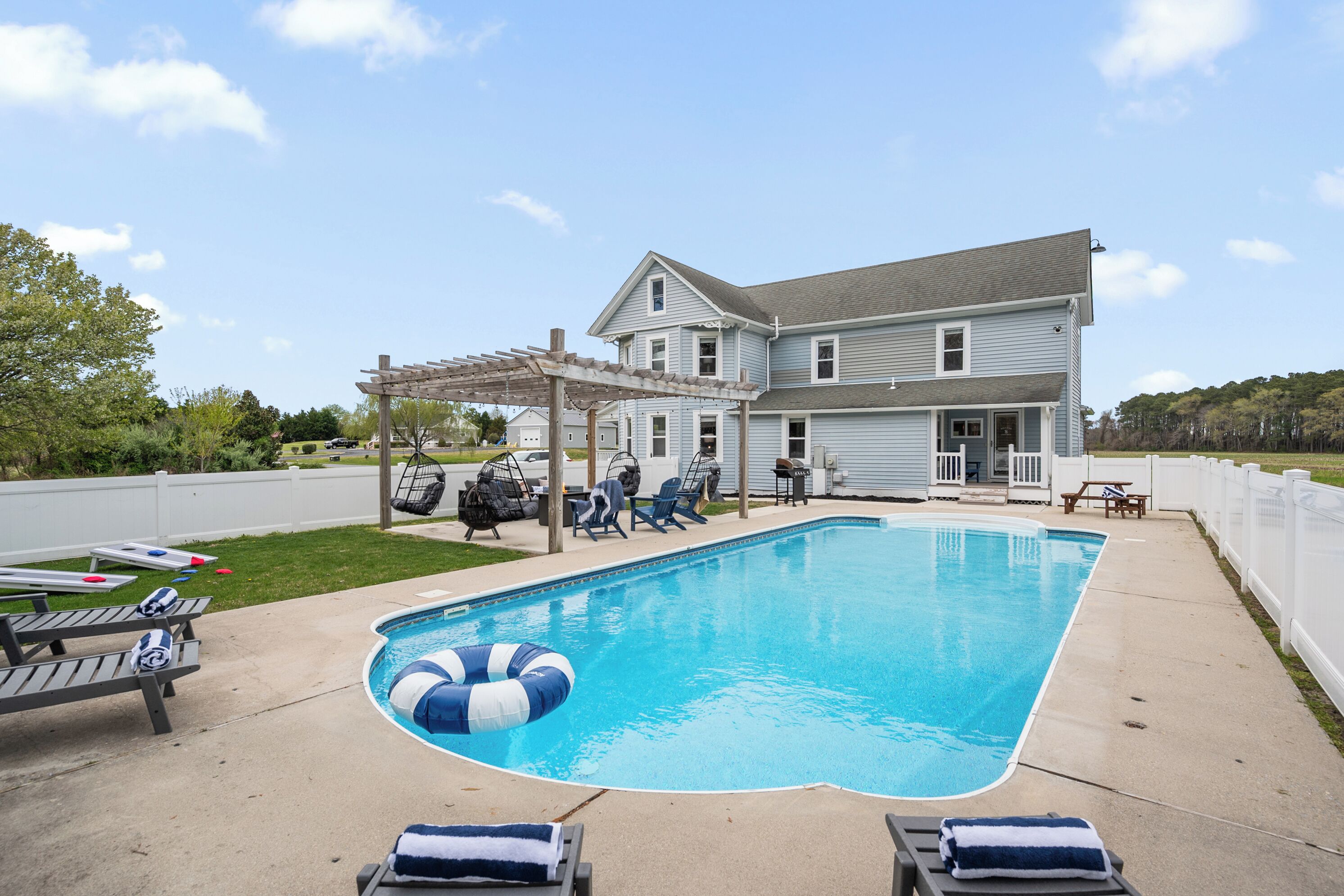 A backyard with a swimming pool, lounge chairs, and a pergola.