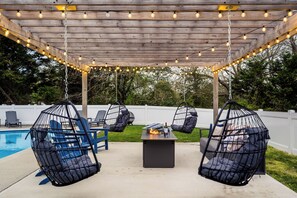 Een overdekt terras met hangstoelen en een zwembad.