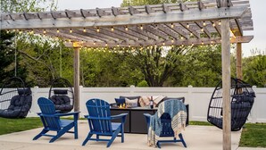 A covered outdoor seating area with string lights, a pool, and a fire pit.