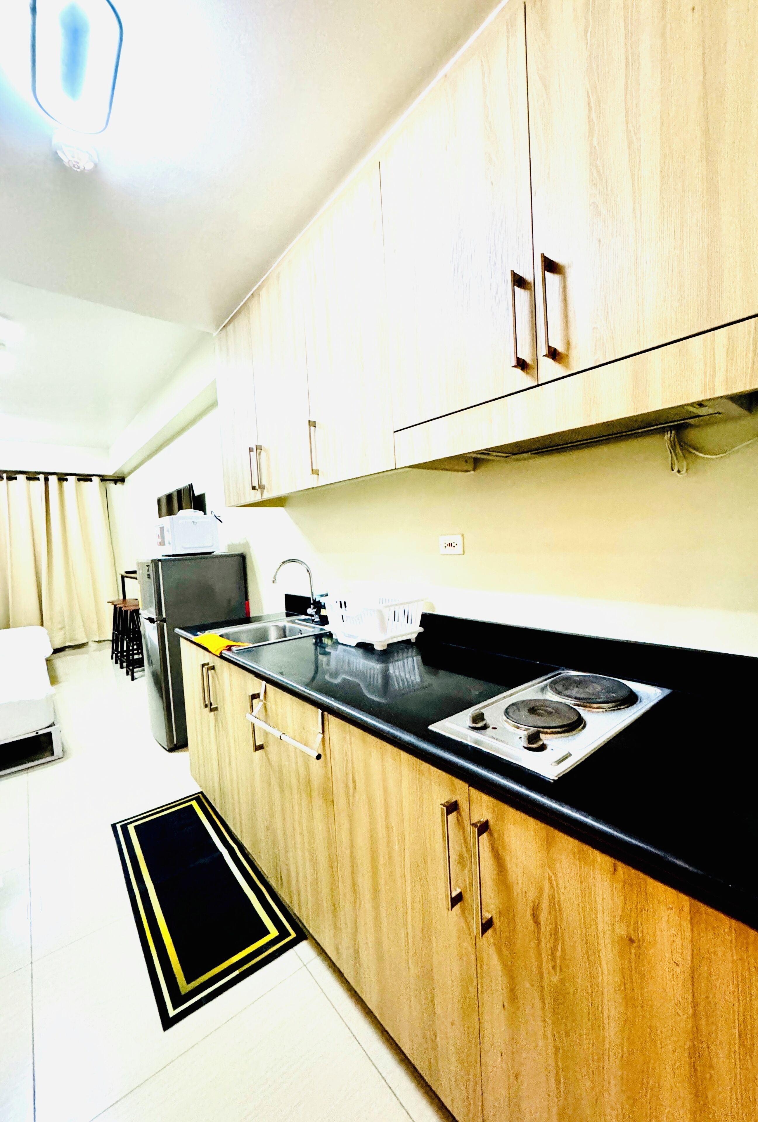 A compact kitchen with wooden cabinets, a black countertop, a stove, and a refrigerator.