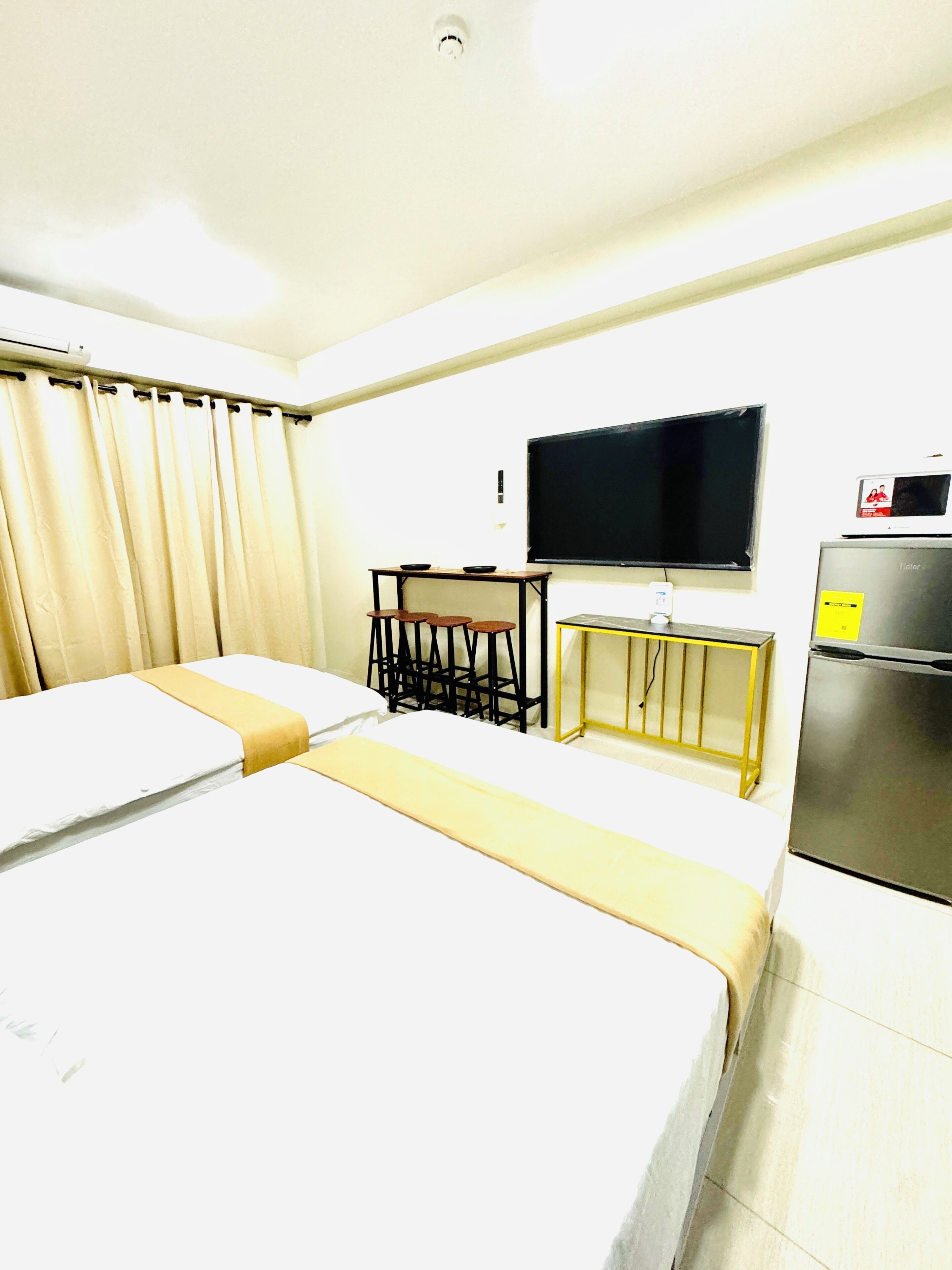 Una habitación de hotel con una cama, un escritorio con silla, televisión y refrigerador.