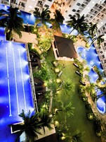 An aerial view of a hotel pool area with a blue pool, surrounding greenery, and a seating area.