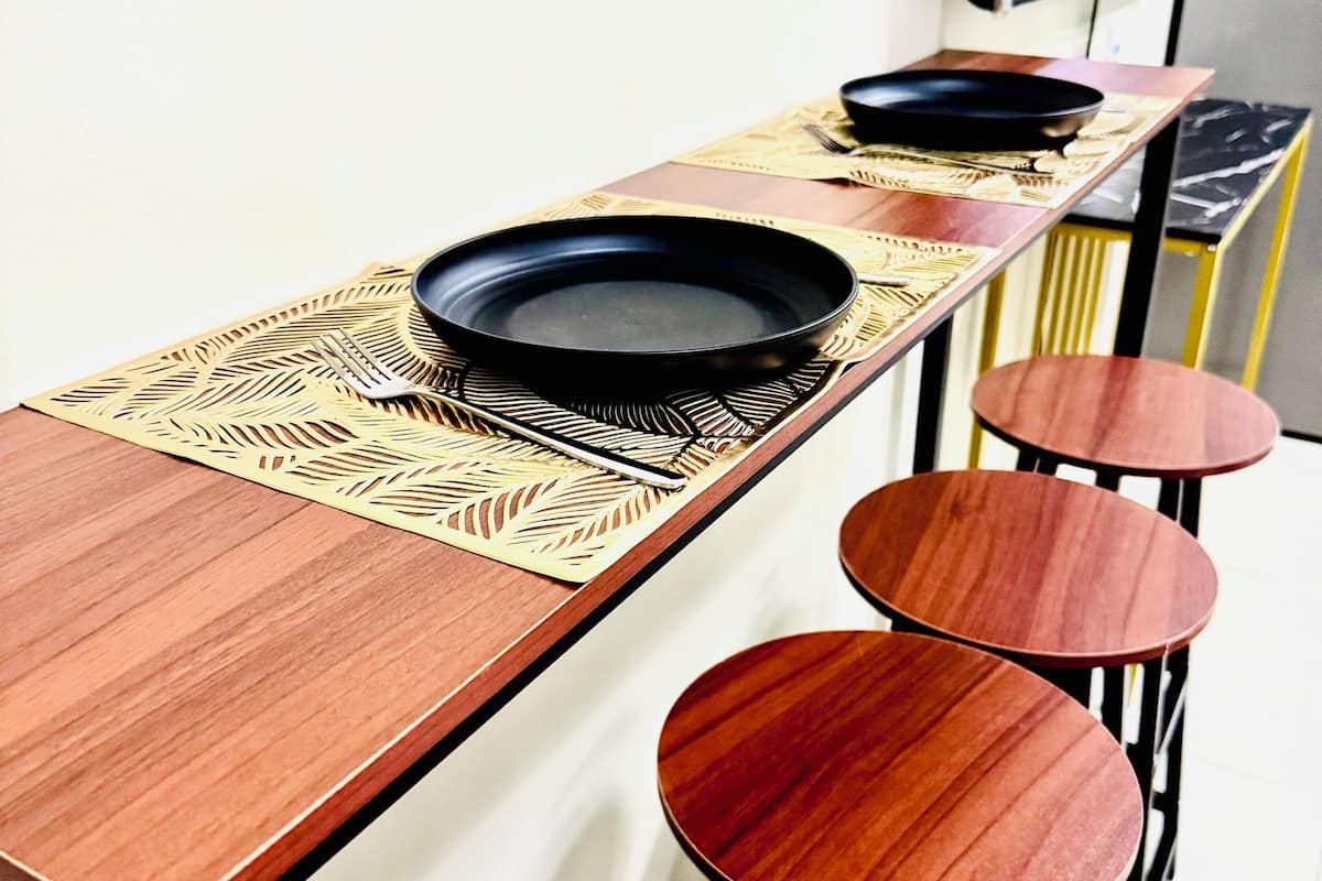 A dining area with a long table and four stools.