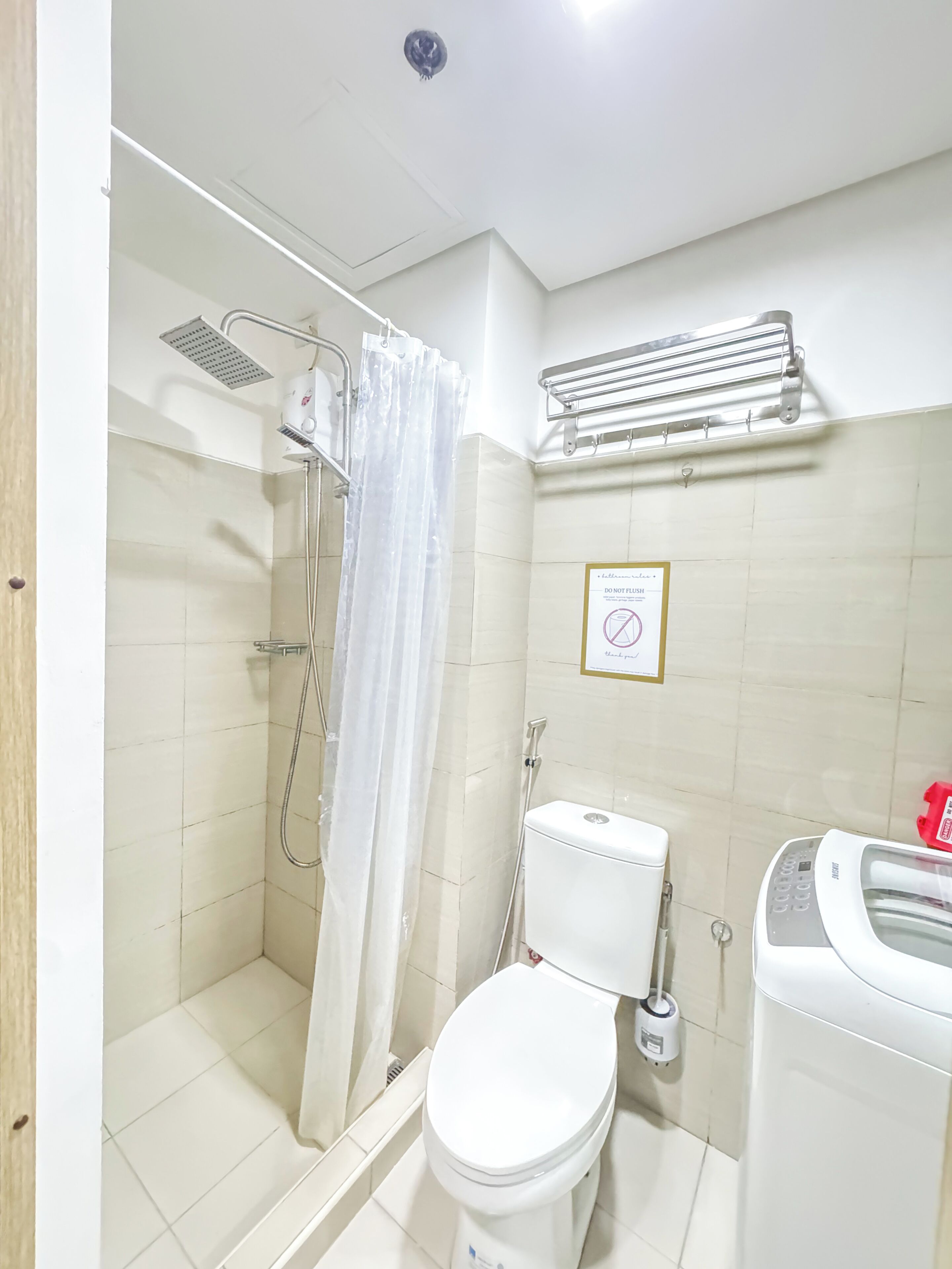 A bathroom with a shower, toilet, and a hand dryer.
