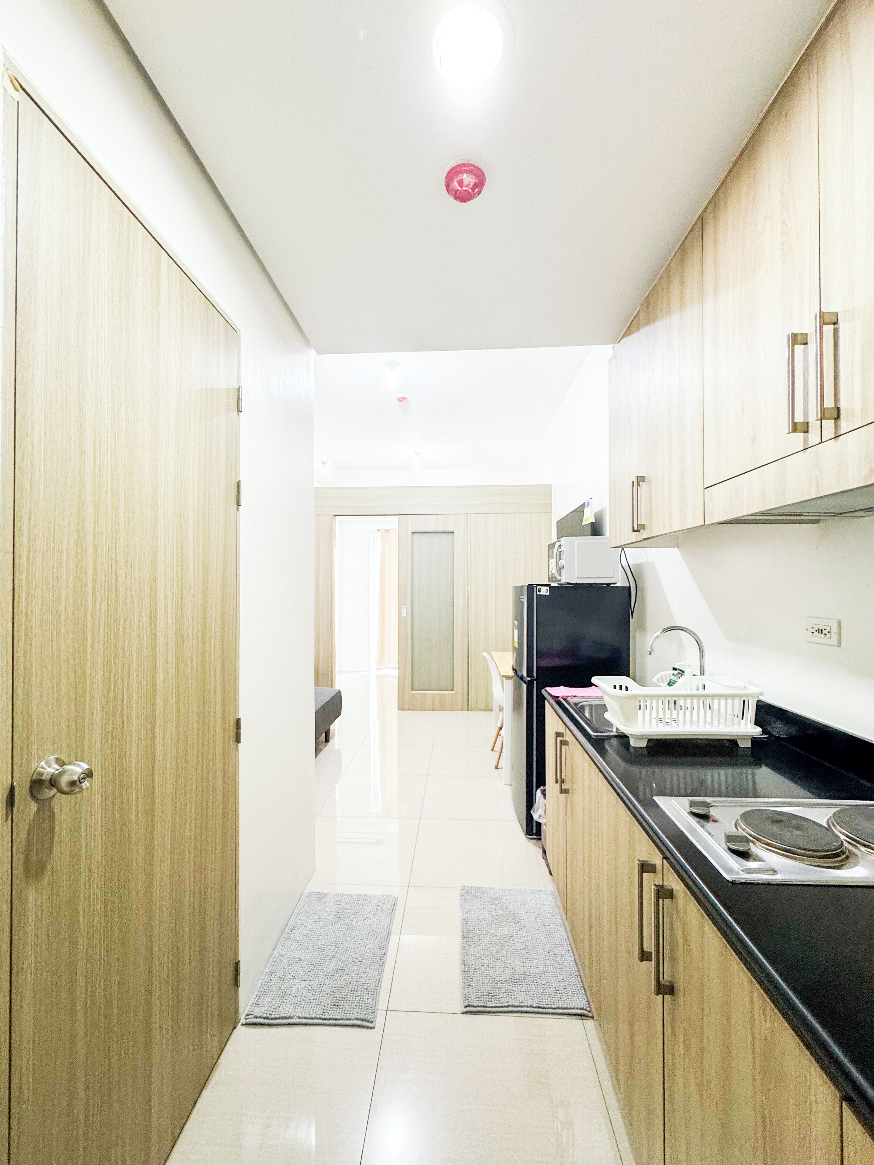 A modern kitchen with wooden cabinets, a black countertop, and a stainless steel sink.