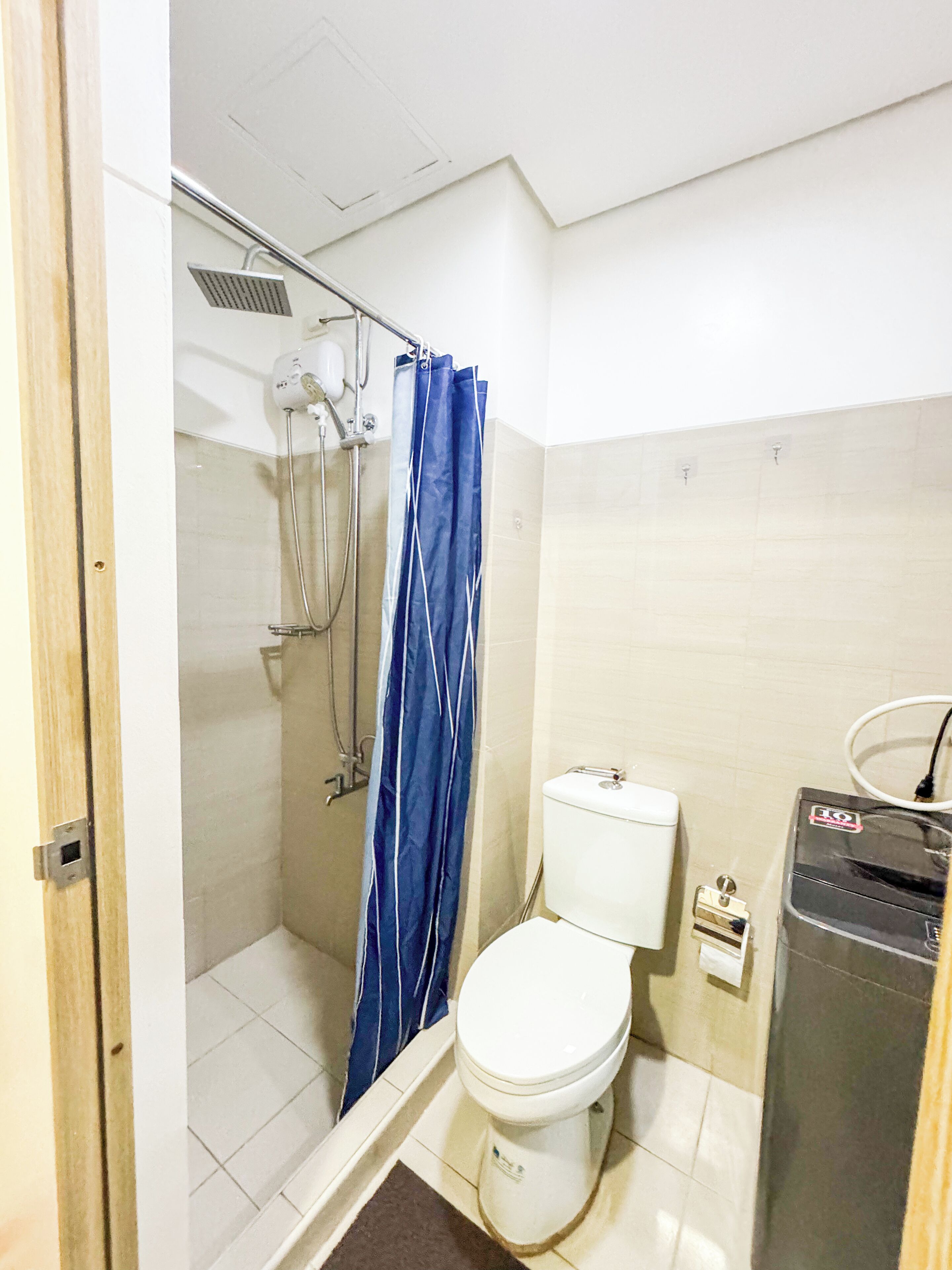 Une petite salle de bain avec douche, toilettes et chauffe-eau.