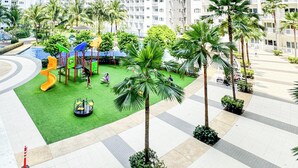 Zona residencial con edificios de apartamentos altos, un parque infantil con toboganes y palmeras.