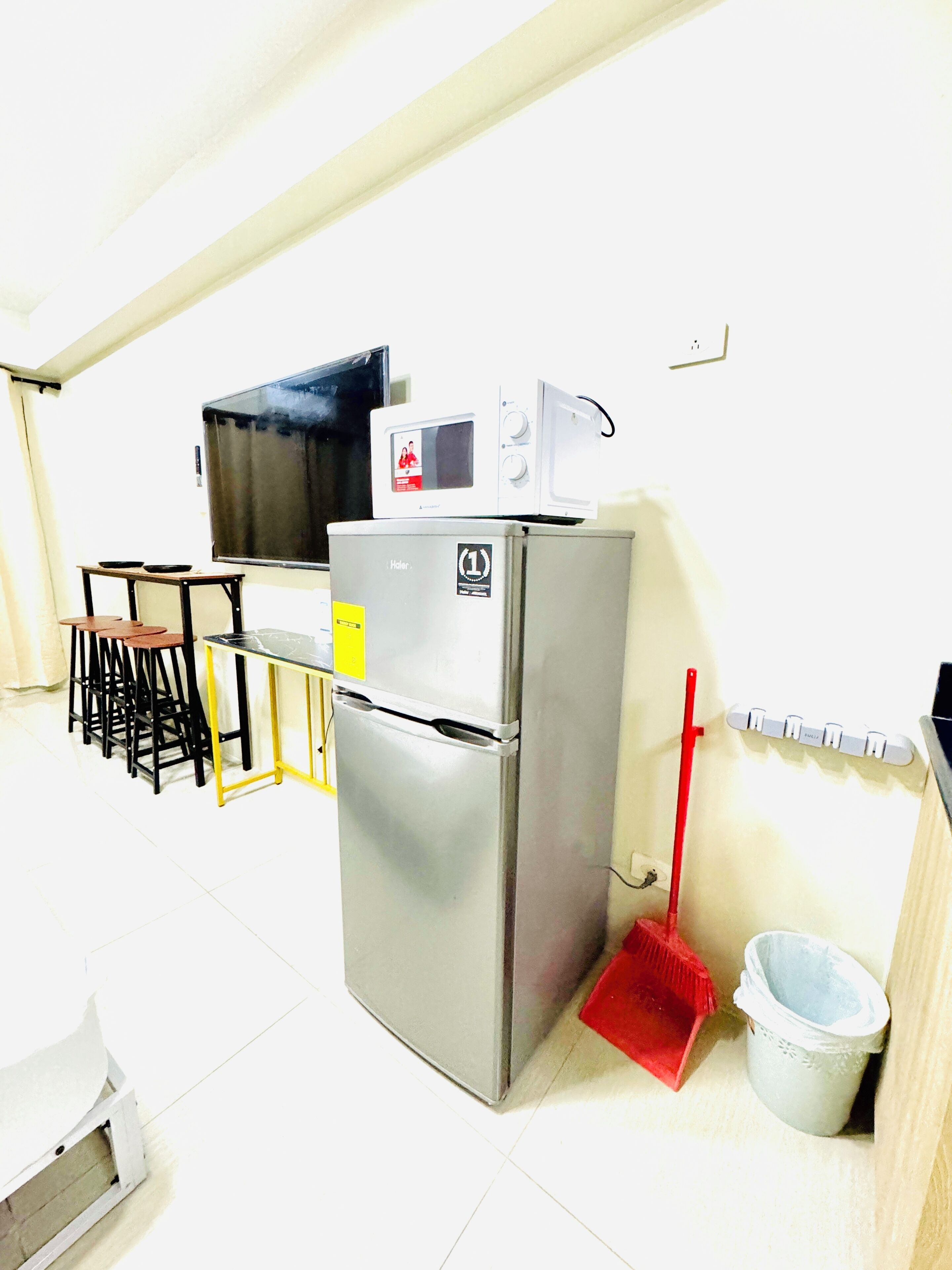 A compact kitchen with a refrigerator, microwave, and a small dining area with stools.