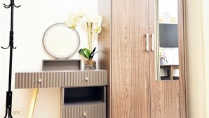 Un dormitorio moderno con un armario de madera, una tocador con espejo y una lámpara de trípode.
