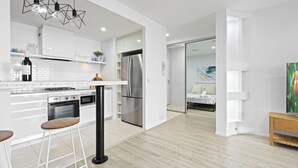 A modern kitchen with white cabinetry, stainless steel appliances, and a bar stool.