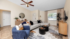 A modern living room with a sectional sofa, a round coffee table, and a wooden console. - Summer Safari - GORGEOUS Home Near Busch Gardens & USF (Tampa)