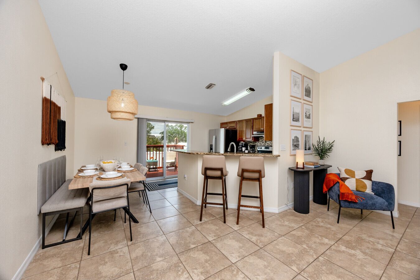 A modern kitchen with a dining area, a bar, and a seating area with a blue sofa.