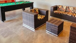 A modern living room with a pool table, two sofas with floral cushions, and a dining area with chairs and a refrigerator. - Recanto Três Amores Private Pool Olímpia (Olímpia)