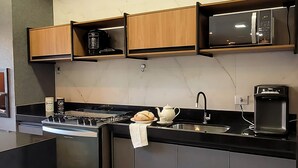 A modern kitchen with dark cabinets, a built-in stove, and a microwave above the counter. - Recanto Três Amores Private Pool Olímpia (Olímpia)