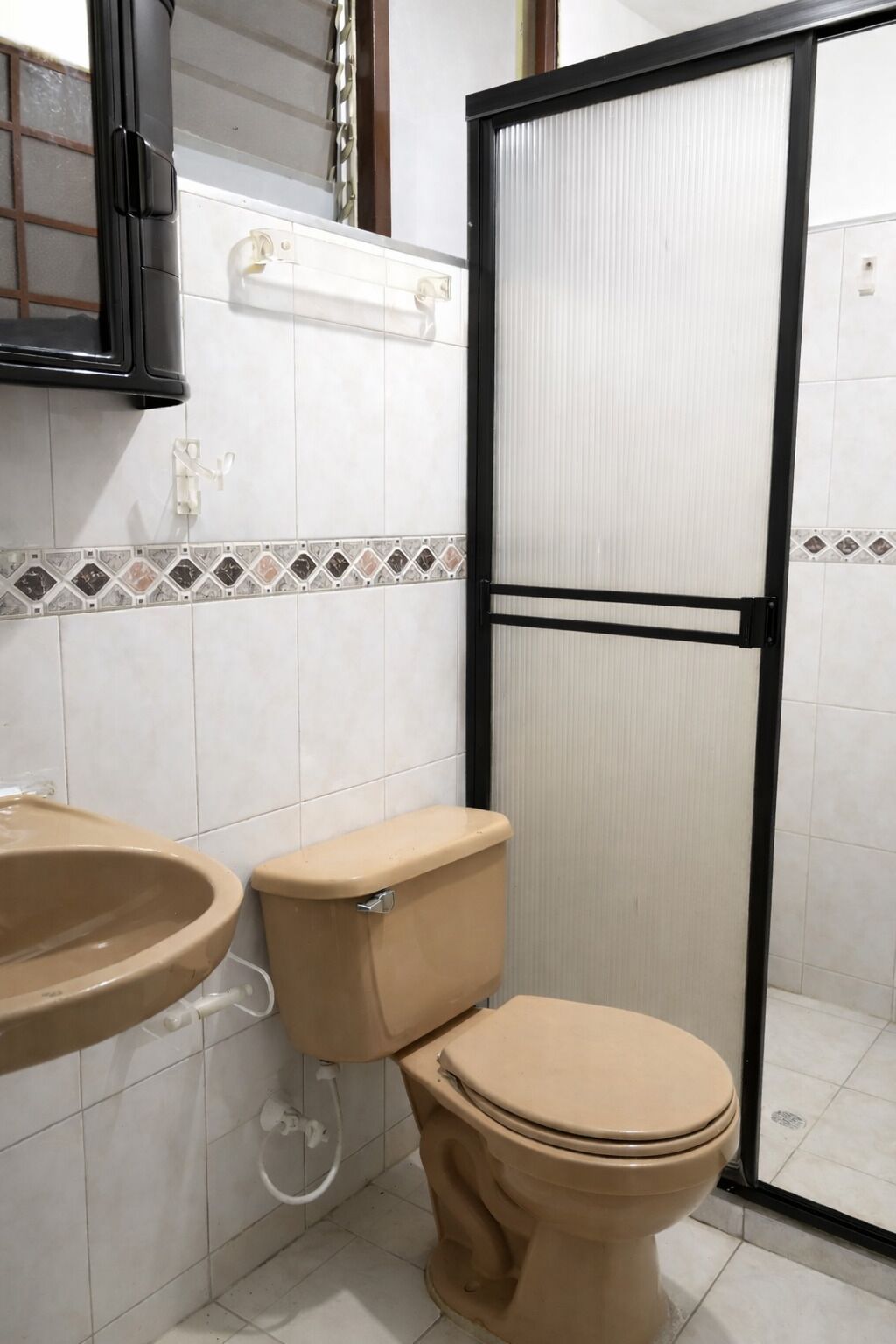 A bathroom with a toilet, sink, and a shower enclosure.