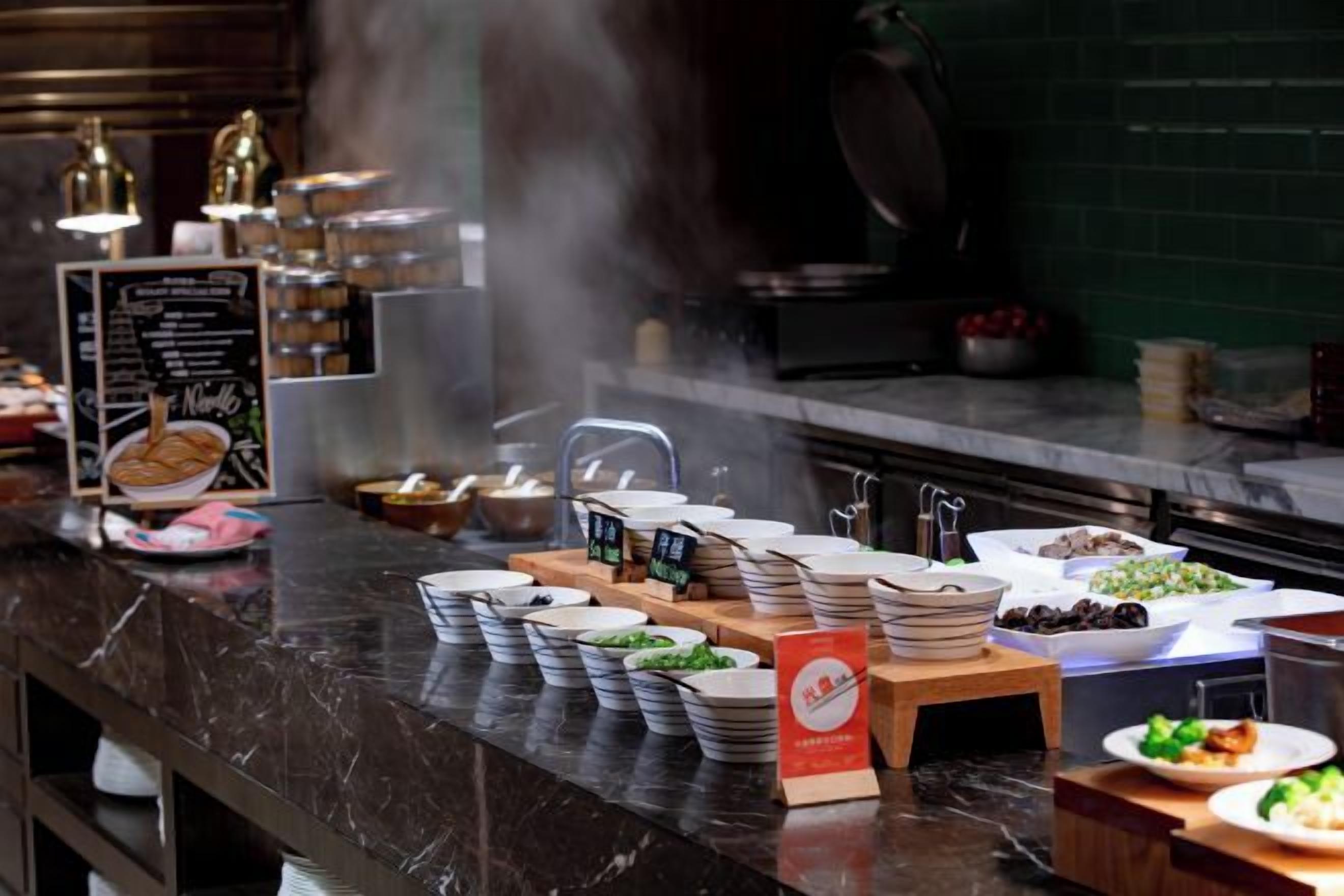 A buffet setup with various dishes and utensils.