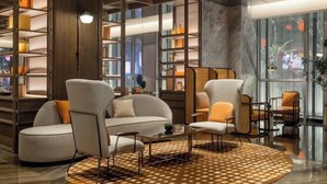 A modern lounge area with a round coffee table, comfortable seating, and built-in shelving with decorative items. - Canopy by Hilton Xi'an Qujiang (Xi'an)
