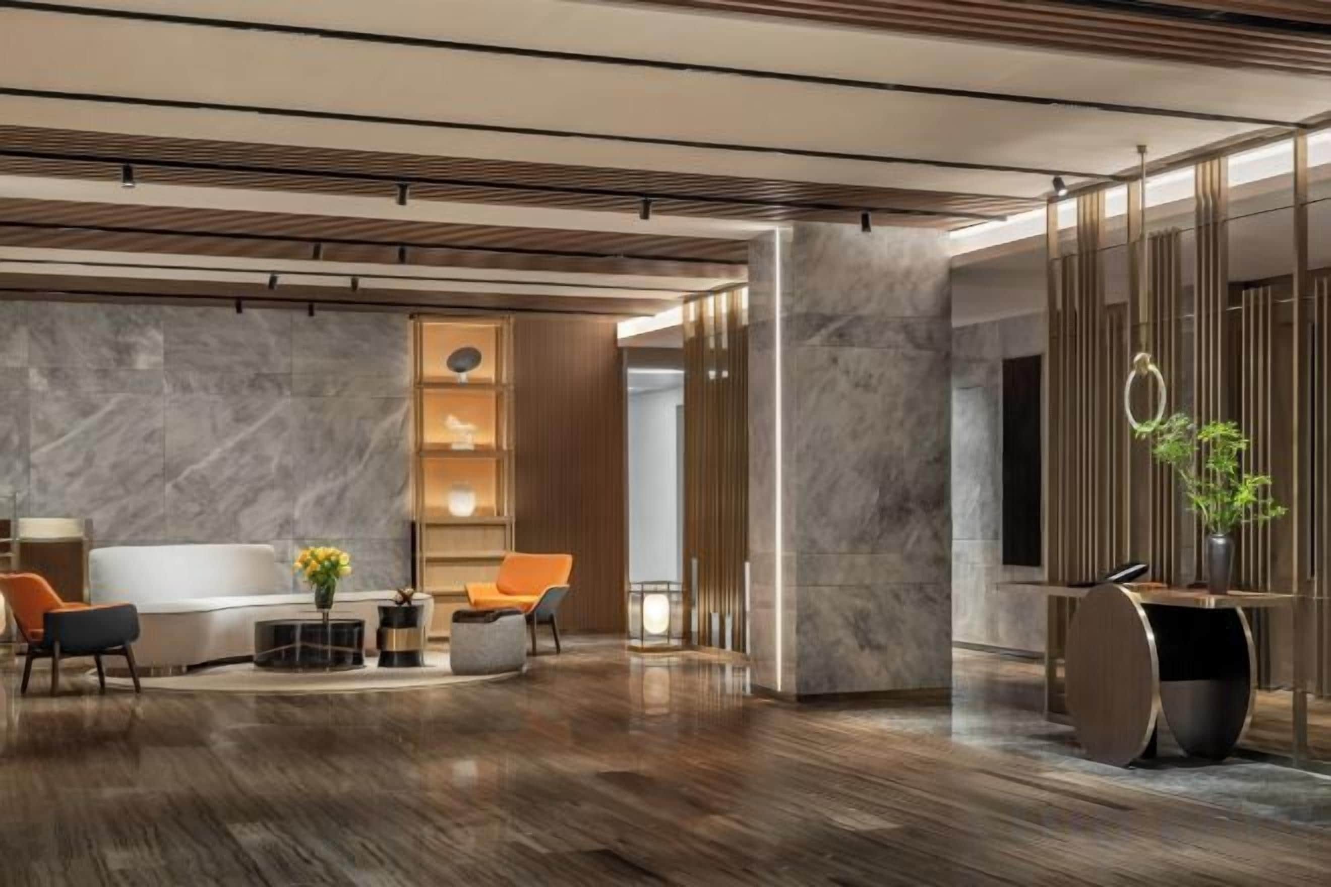 Eine moderne Lobby mit einem Marmor-Empfangstresen, einer Sitzecke und einer Pflanze.