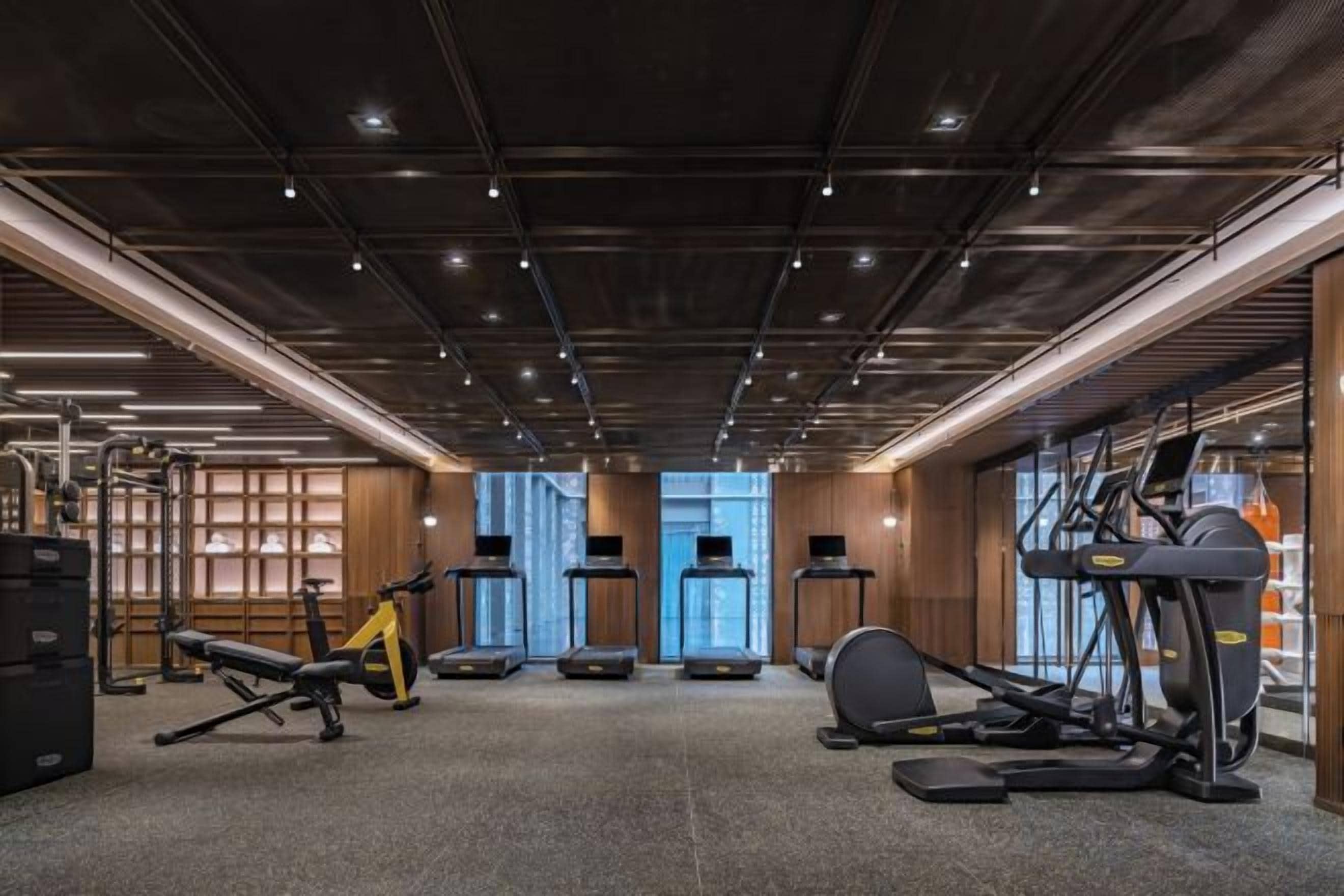 Un gimnasio con cintas de correr, elípticas y equipo de levantamiento de pesas.