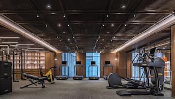 Un gimnasio con cintas de correr, elípticas y equipo de levantamiento de pesas.