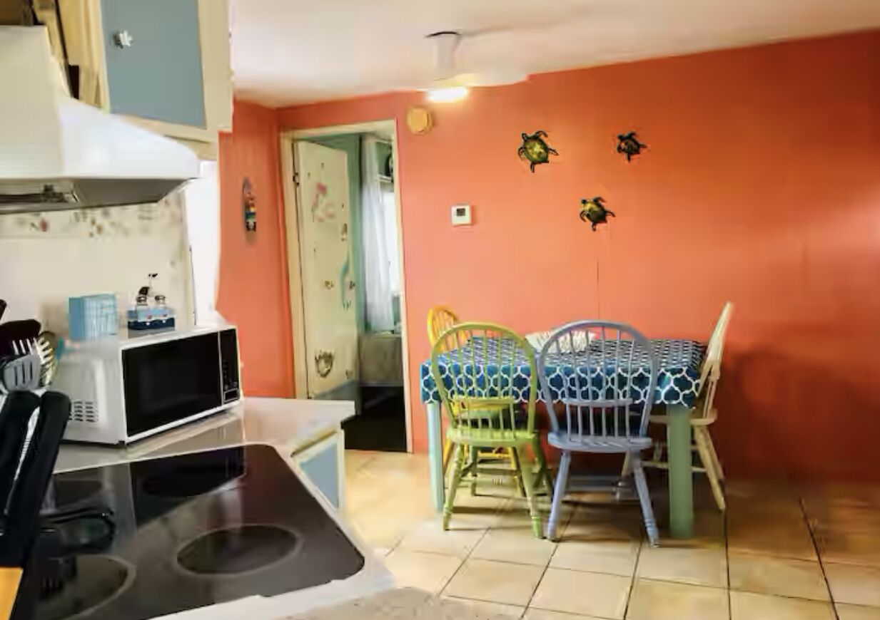 Una cocina con microondas, estufa y sillas alrededor de una mesa.