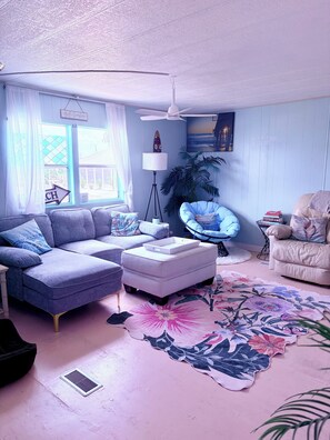 A living room with a sofa, ottoman, chair, floor lamp, and a large floral rug.