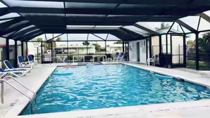 A swimming pool with a covered area, lounge chairs, and a lifeguard stand.