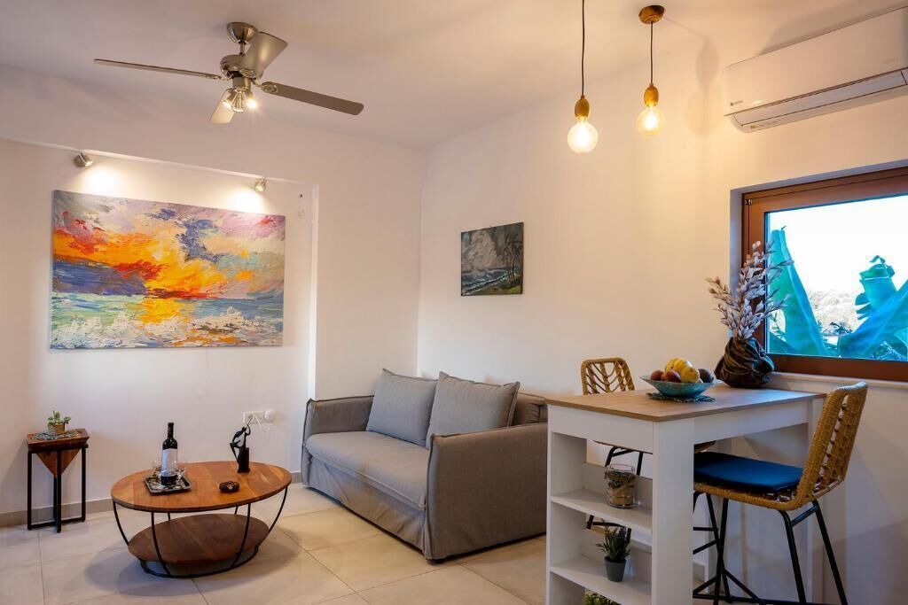 A modern living room with a sofa, a coffee table, a dining table with chairs, and artwork on the walls.