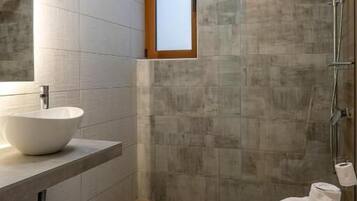 Un baño moderno con un lavamanos grande, un inodoro y una zona de ducha.