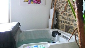 A room with a hot tub, a painting on the wall, and a large plant.