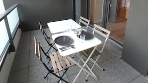 En balkon med et bord dækket til to, en stol og udsigt over indretningen.