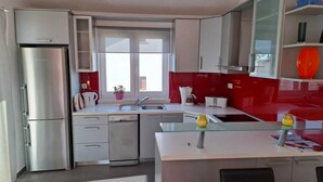 Een moderne keuken met roestvrijstalen apparatuur, een vaatwasser en een raam dat voor natuurlijk licht zorgt.