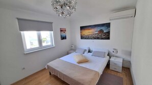Een slaapkamer met een bed, twee nachtkastjes, een raam en een schilderij aan de muur.