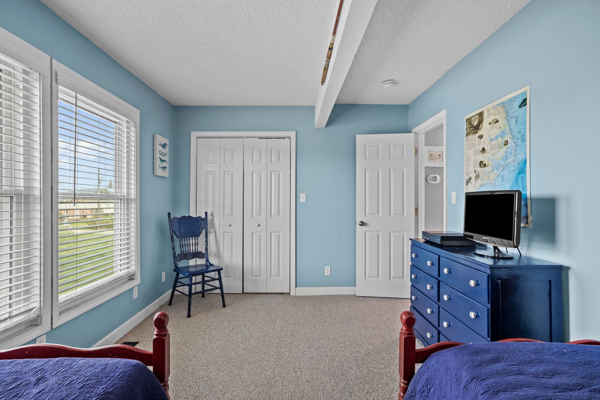 A bedroom with two beds, a dresser, a chair, and a TV.