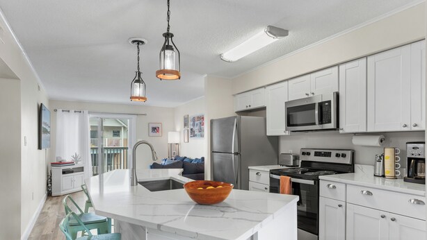 Una cocina moderna con armarios blancos, electrodomésticos de acero inoxidable y una isla central con un lavabo.