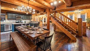 A spacious wooden interior with a dining area, kitchen, and a staircase. - Large Game Garage, Fire Pit, Hot Tub, Mt. LeConte Views! (Sevierville)