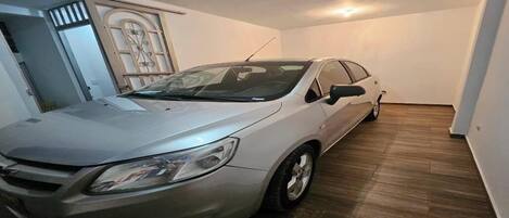 A car parked inside a room with wooden flooring and white walls.