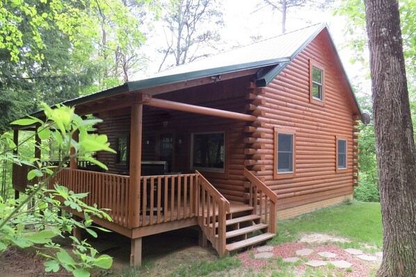 A log cabin with a porch, a covered entryway, and a small staircase leading to the entrance.