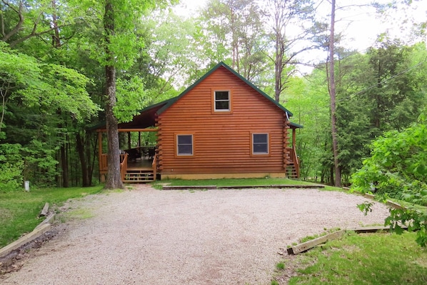 Eine Holzhütte mit Veranda, umgeben von Bäumen.