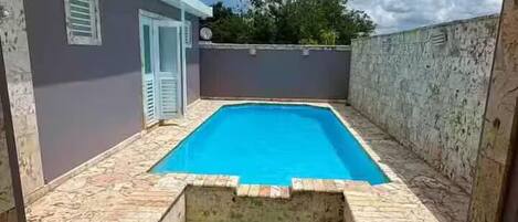 A swimming pool with a stone deck and a small hot tub area.